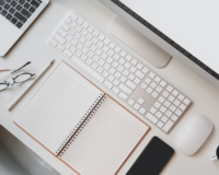 work desk with notebook, keyboard, and phone